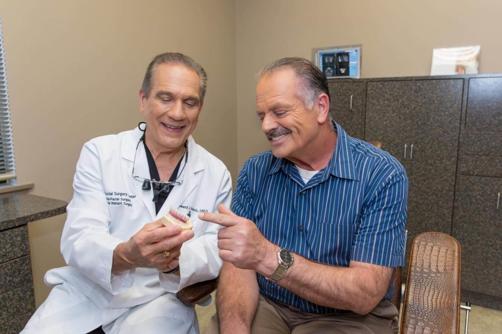 dr halusic with patient viewing dental implant model