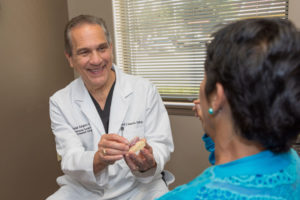 Dr. Halusic Showing A Dental Patient A Full Arch Dental Implant Model