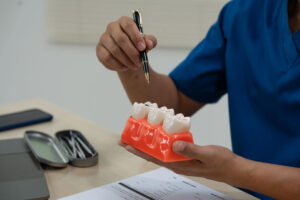 A male doctor sits working at the table in a dentist's clinic, explaining tooth decay, wisdom teeth, broken teeth, false teeth, and recommended treatments to patients.