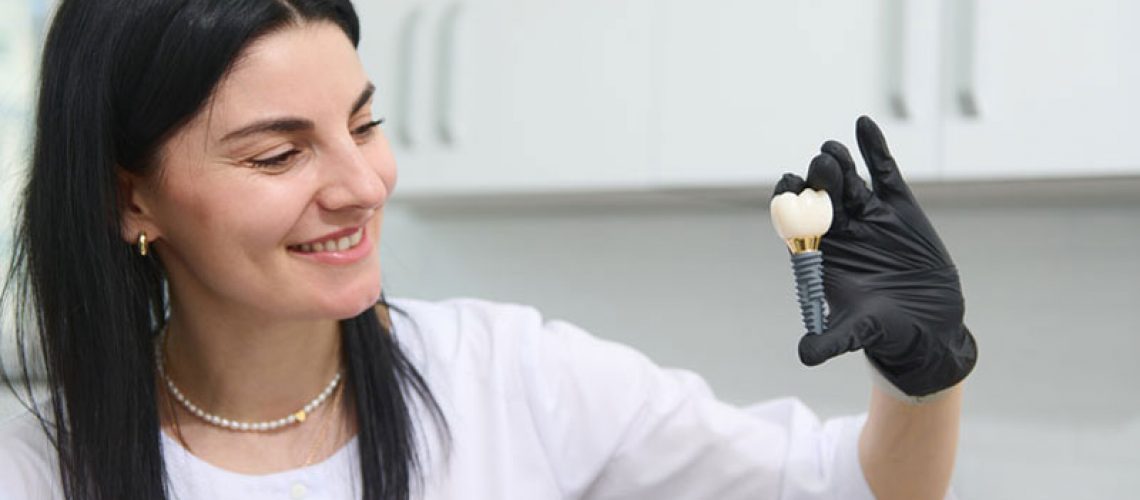 young woman holding dental implant mockup, artificial tooth roots into jaw canal. dental treatment concept