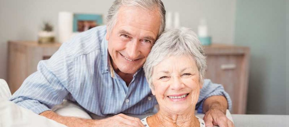 an elderly couple smiling with their new dental implants