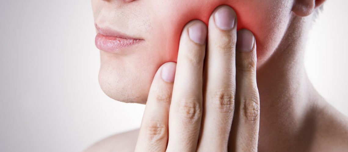 a tooth extraction patient holding her cheek from tooth pain.